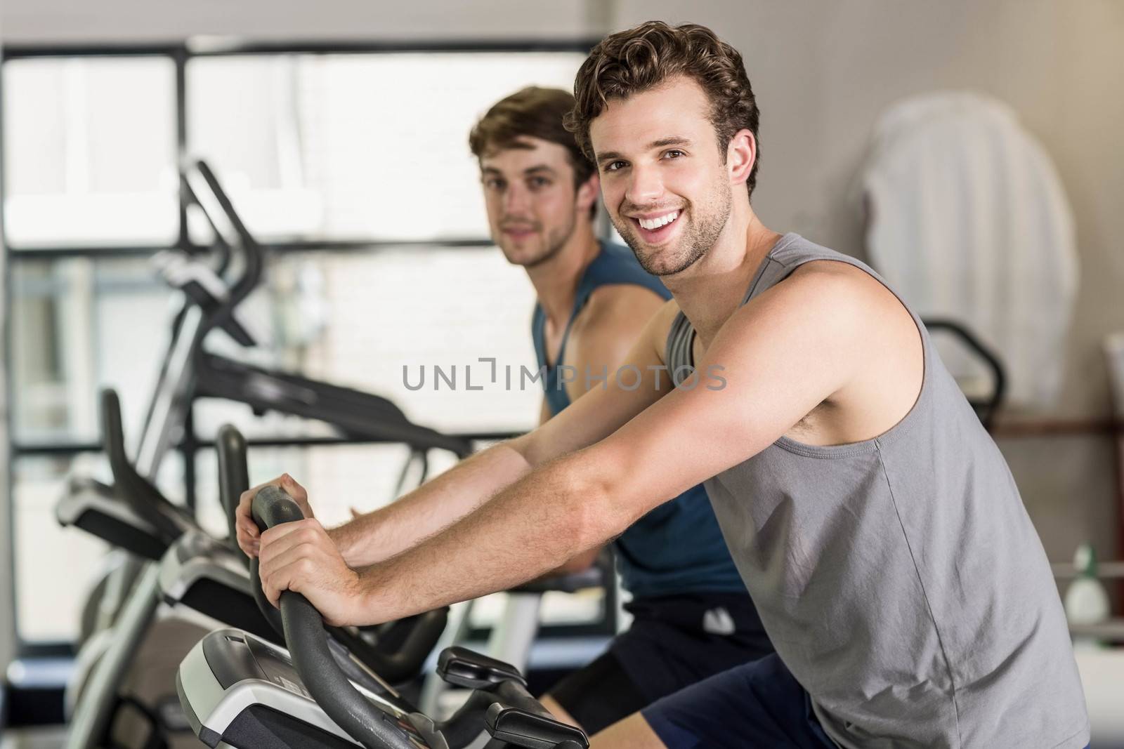 Fit people doing exercise bike at gym