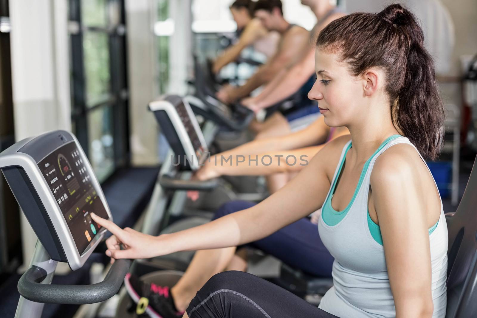 Fit people doing exercise bike at gym