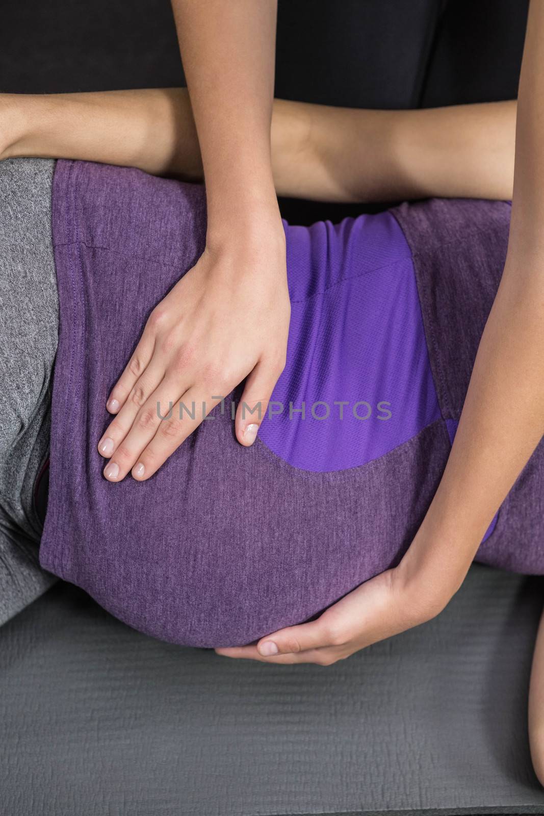 Trainer massaging pregnant woman on exercise mat
