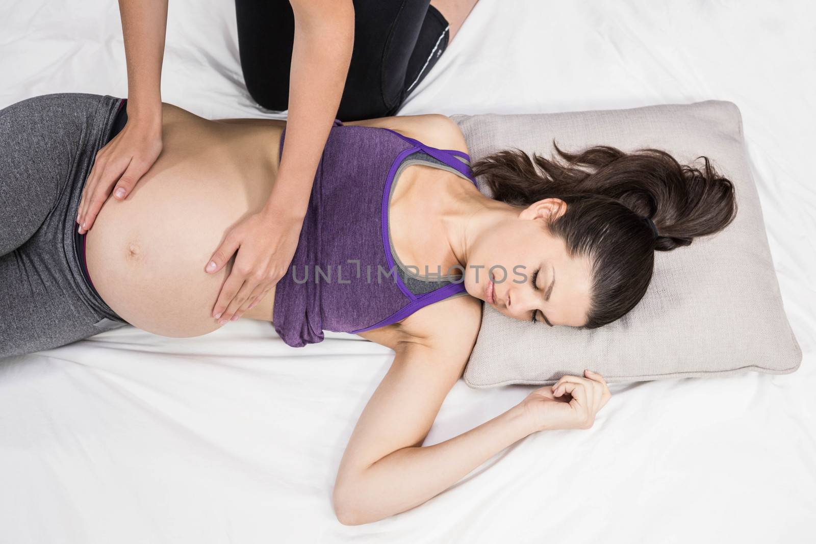 Trainer touching belly of lying pregnant woman by Wavebreakmedia