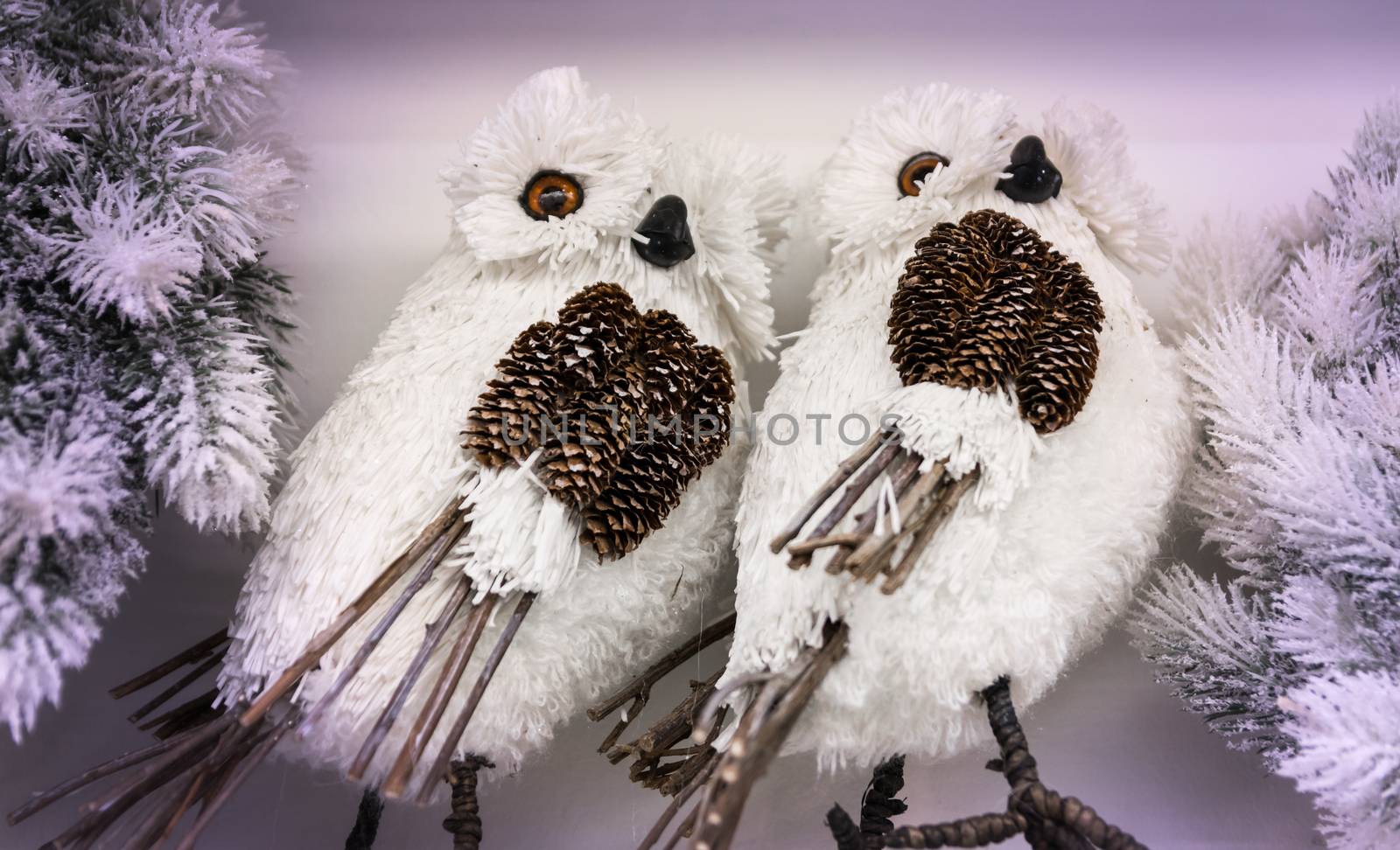 Couple of white owls made from natural materials such as pine cones and twigs.