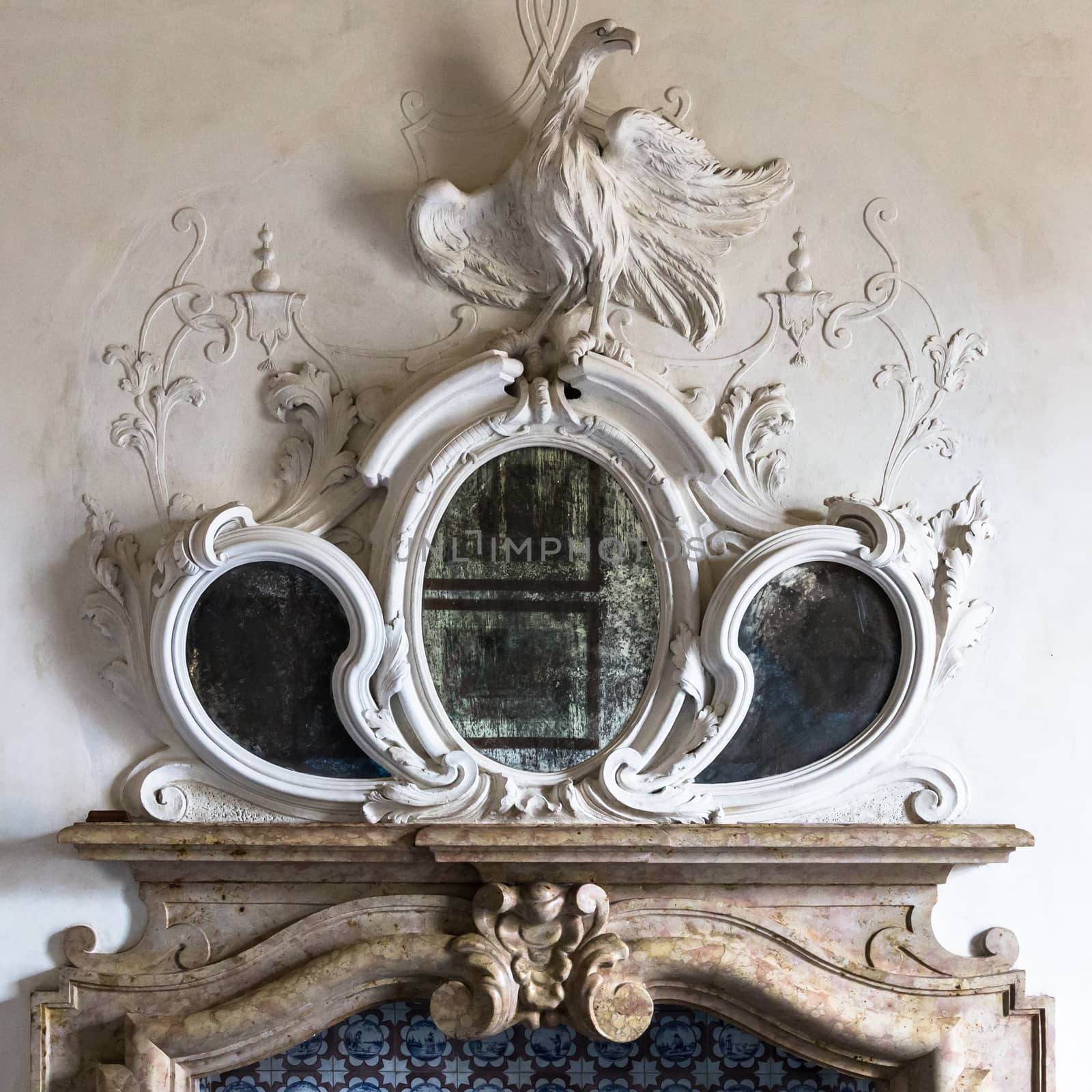 Ornamental mirror above the fireplace of a Venetian villa with sculpture of a phoenix.