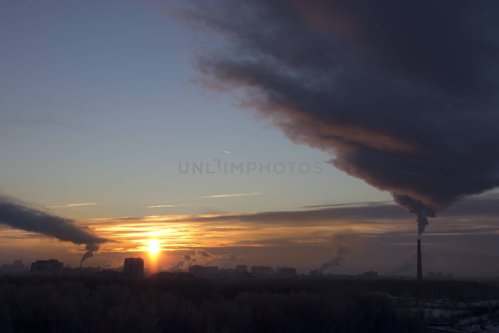 Tube with dark smoke on winter sunset