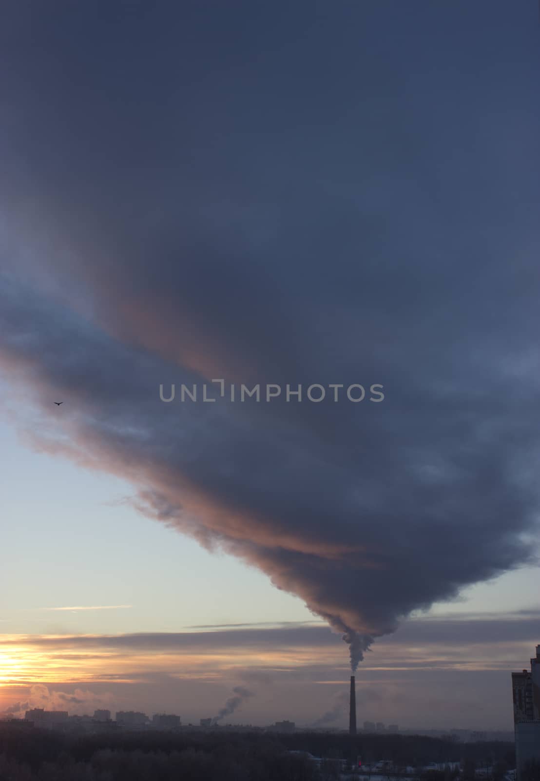 Tube with dark smoke on winter sunset