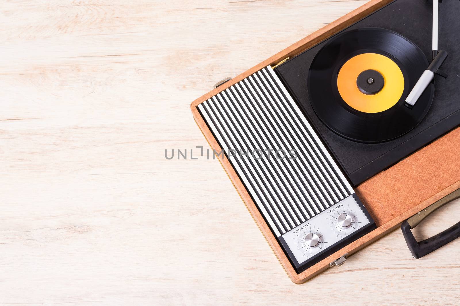 Gramophone with a vinyl record on wooden table, top view and copy space,photo desaturate and split toning for old style.