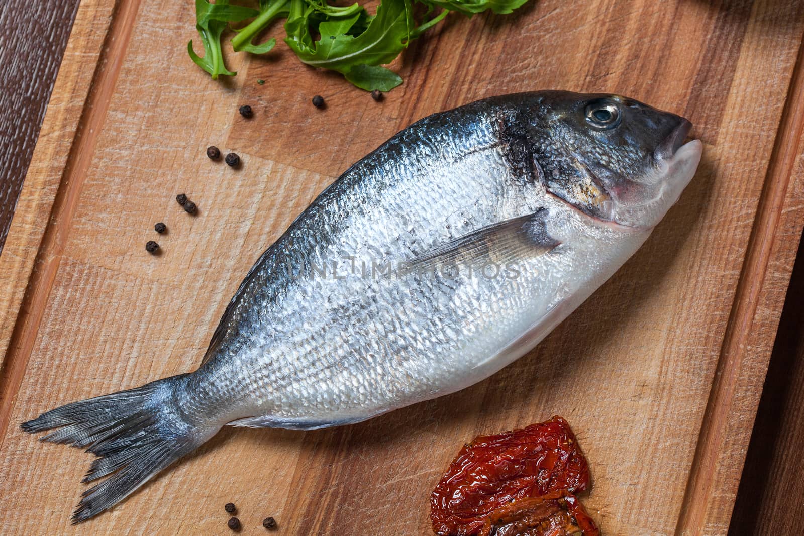 Fresh uncooked dorado fish with ingredients closeup by rozhenyuk