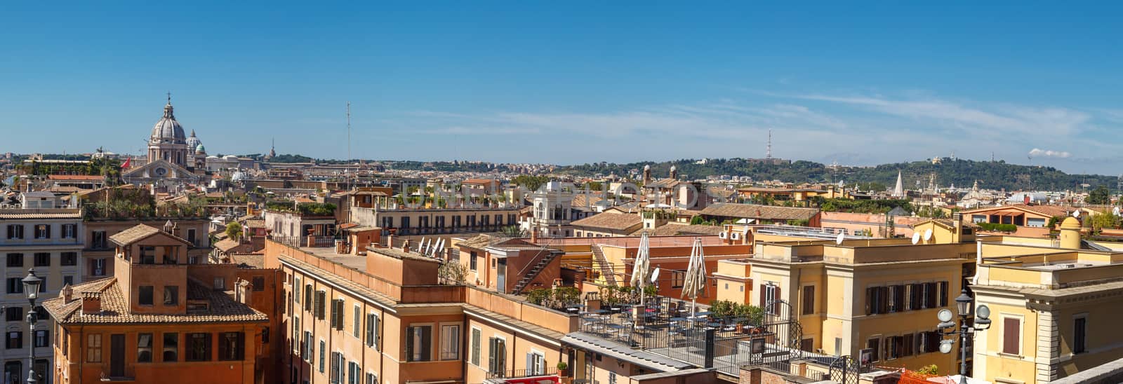 View of Rome with historical buildings from Spanish Steps, on bright blue sky background.
