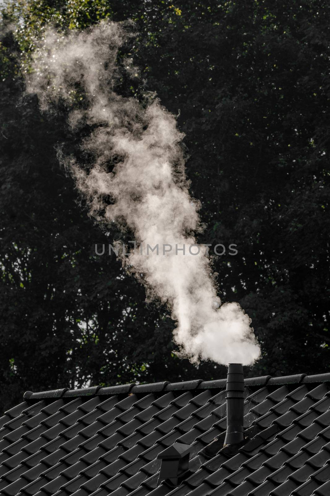 Smoke coming out of a chimney on the roof of a house