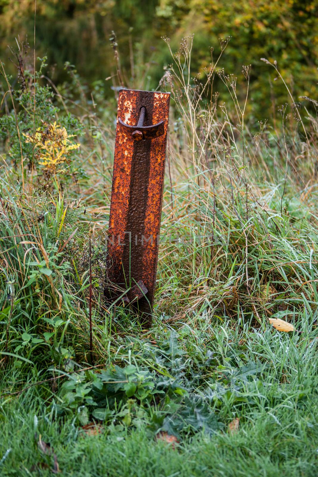 Rusty metal pole on a field by Sportactive