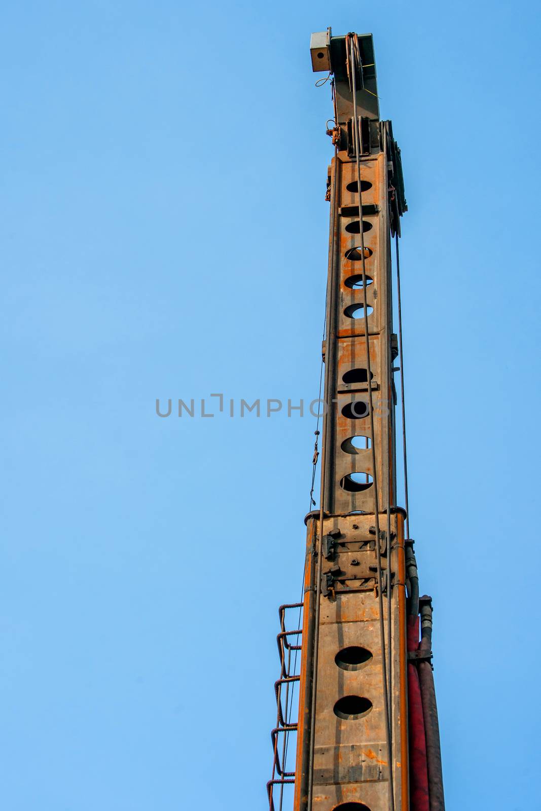 Tall industrial piling machine isolated on blue background