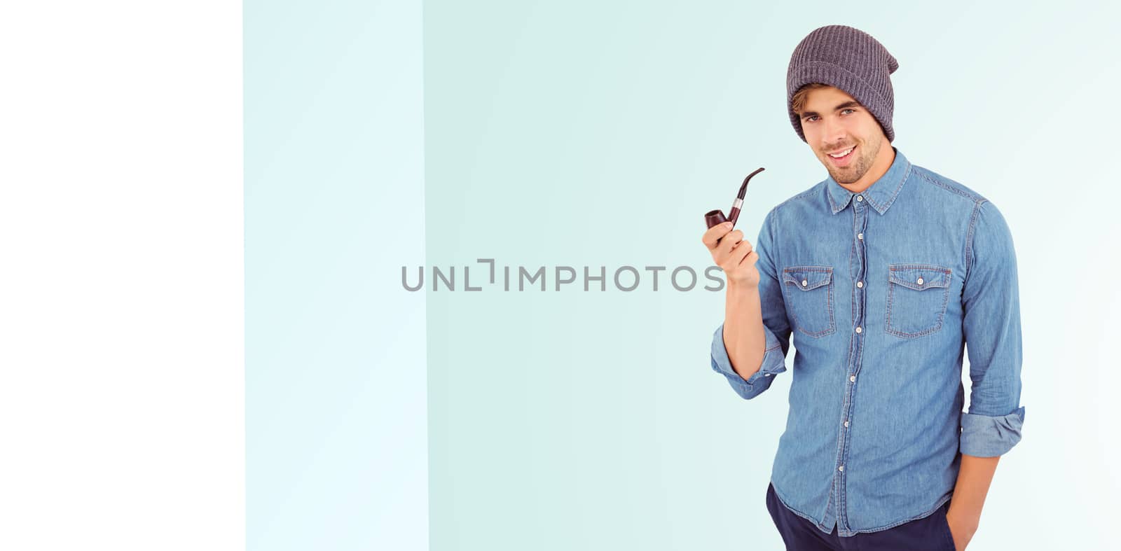 Portrait of hipster smiling while holding smoking pipe against blue background