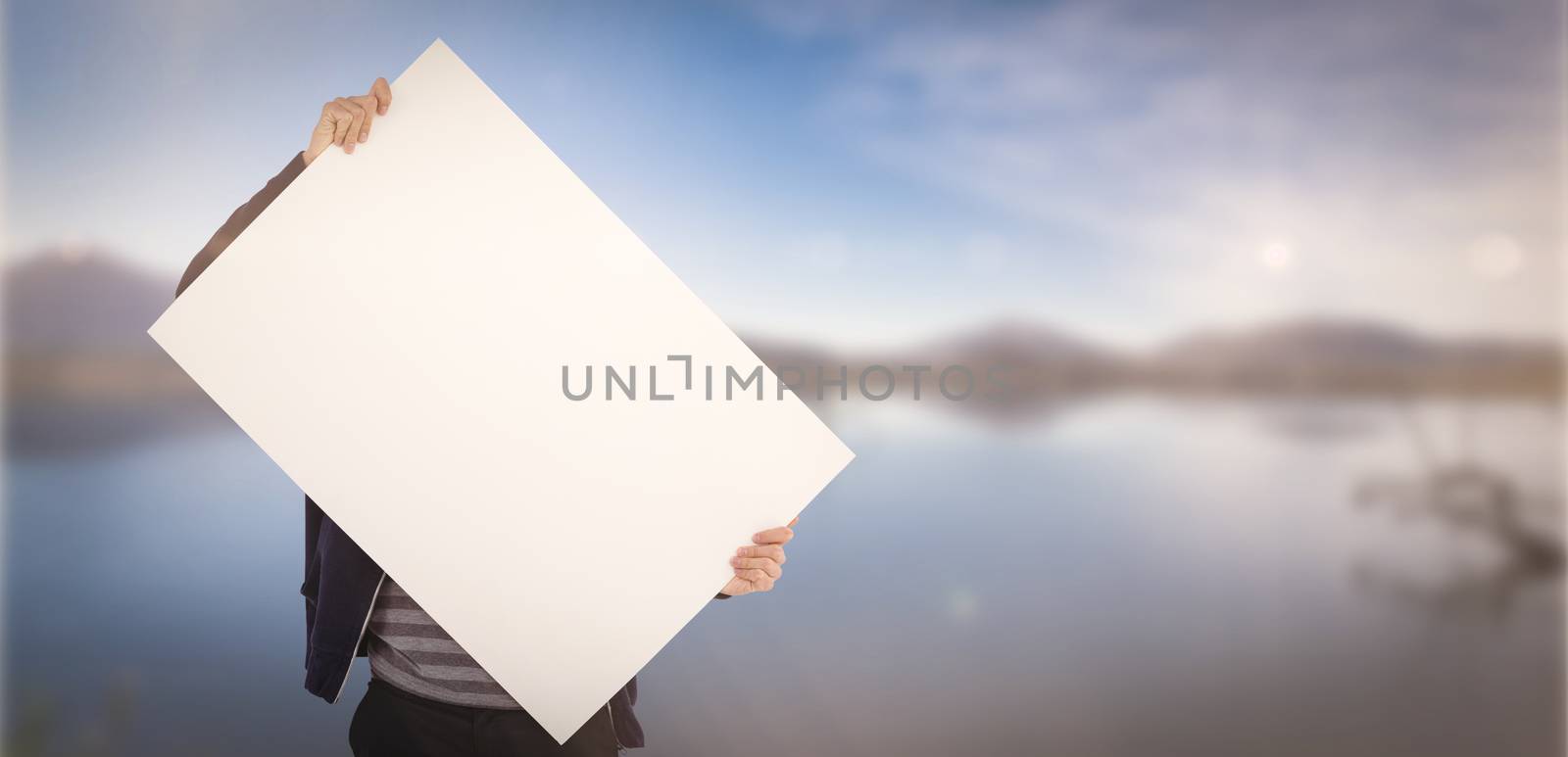 Man holding billboard in front of face against lake