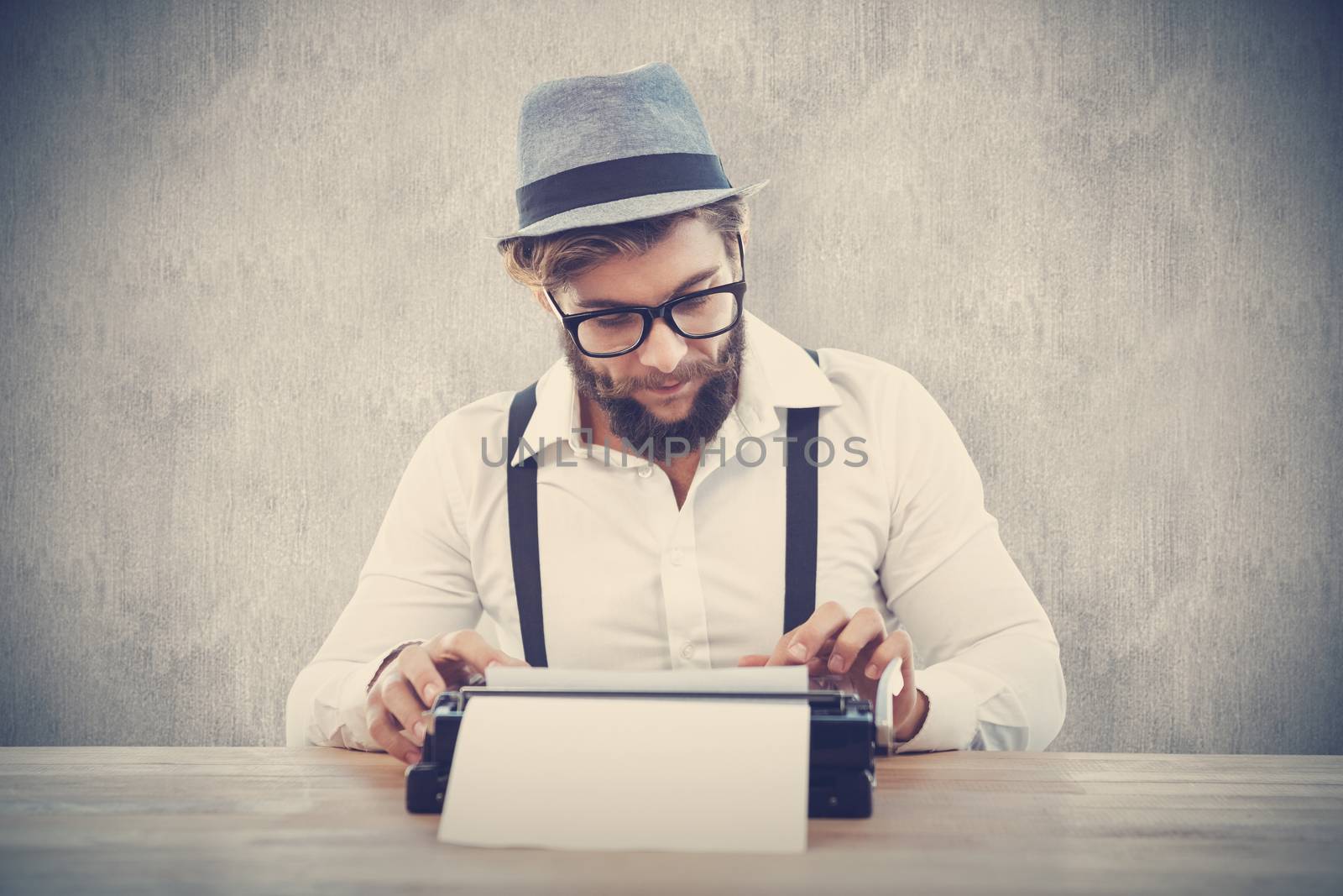 Hipster wearing eye glasses and hat working on typewriter against white and grey background