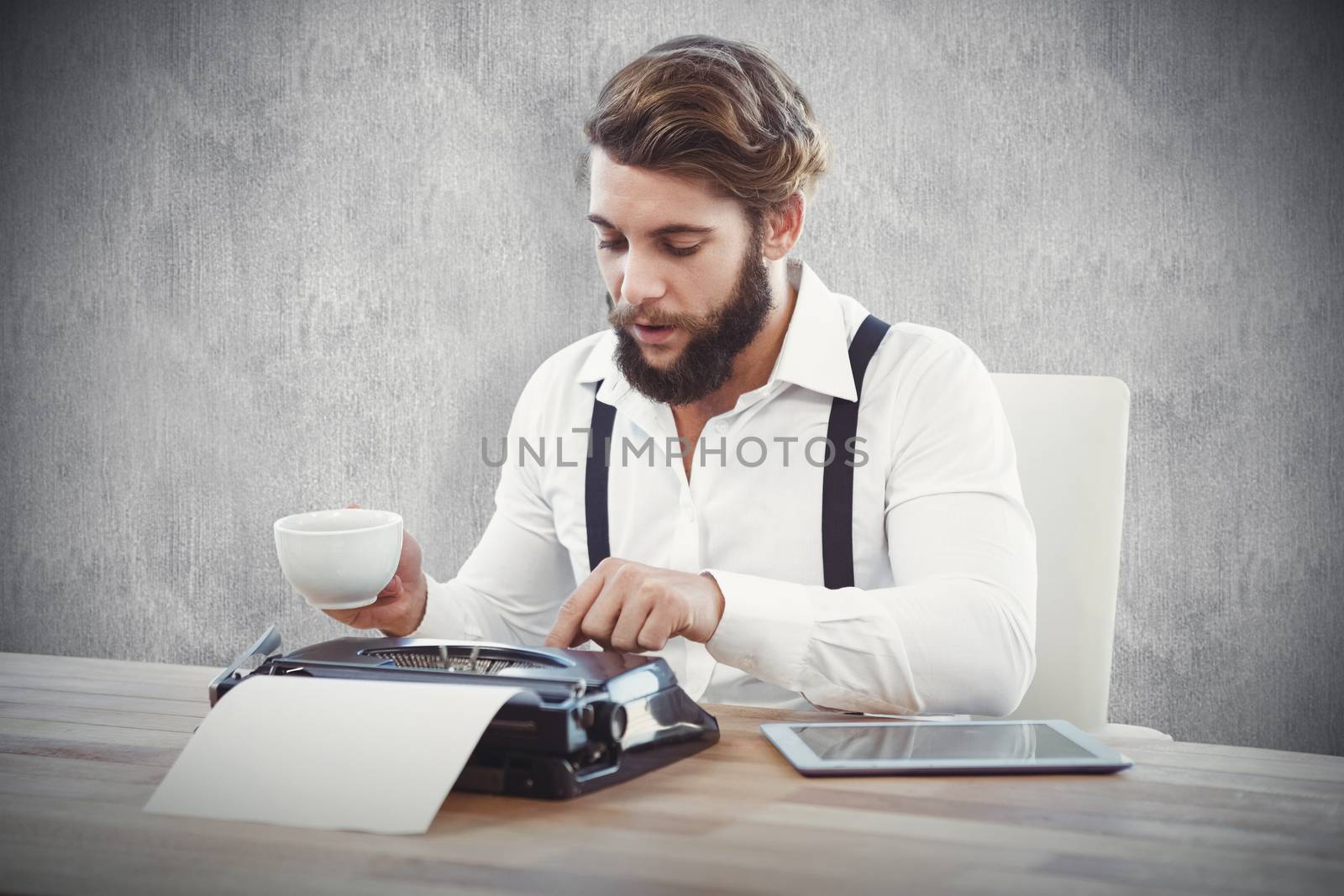 Hipster holding coffee working on typewriter against white and grey background
