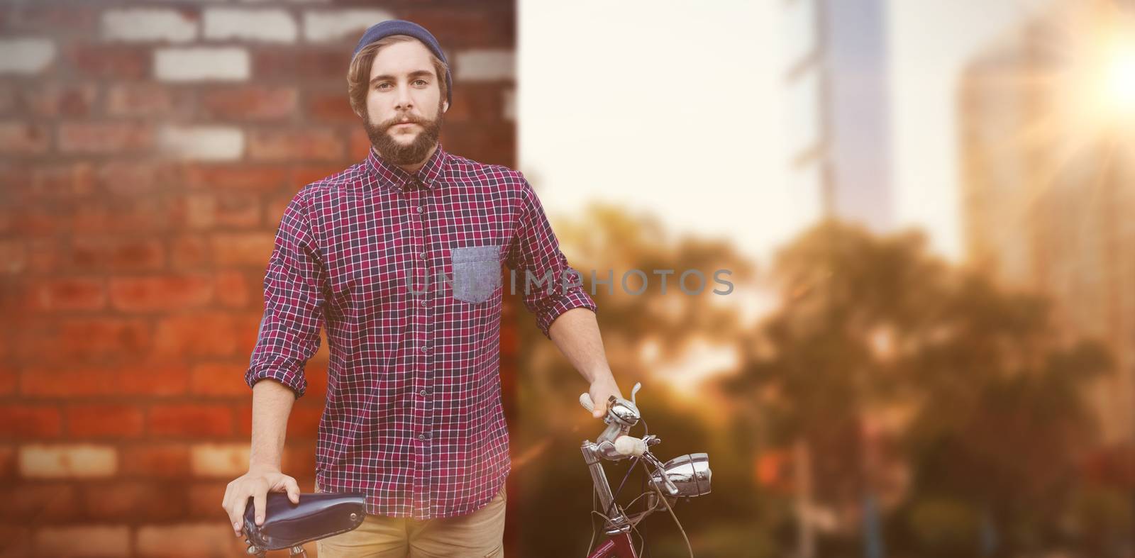 Hipster with bicycle against fence against wall of a house