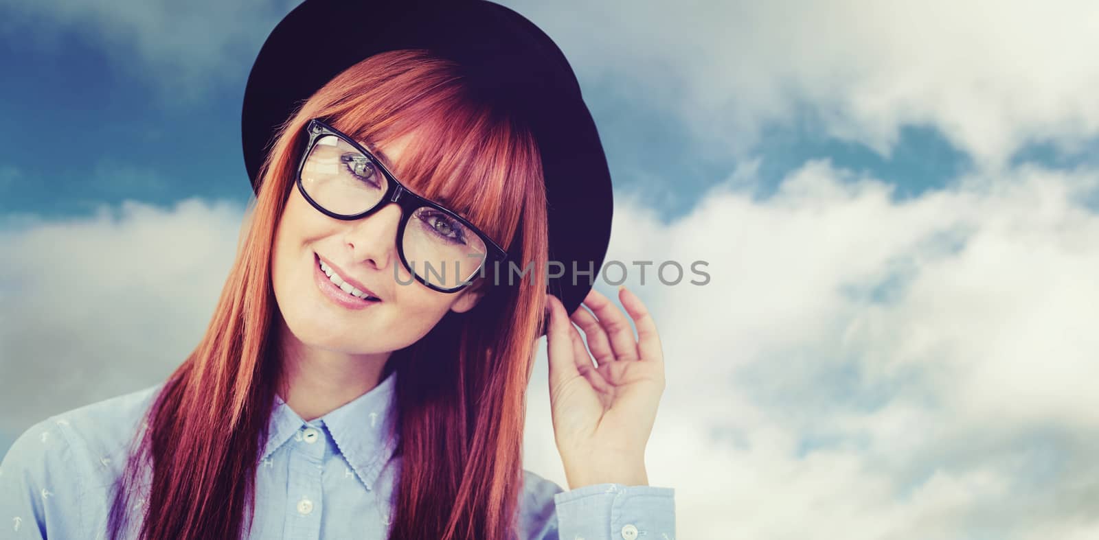 Smiling hipster woman posing face to the camera against blue sky with clouds