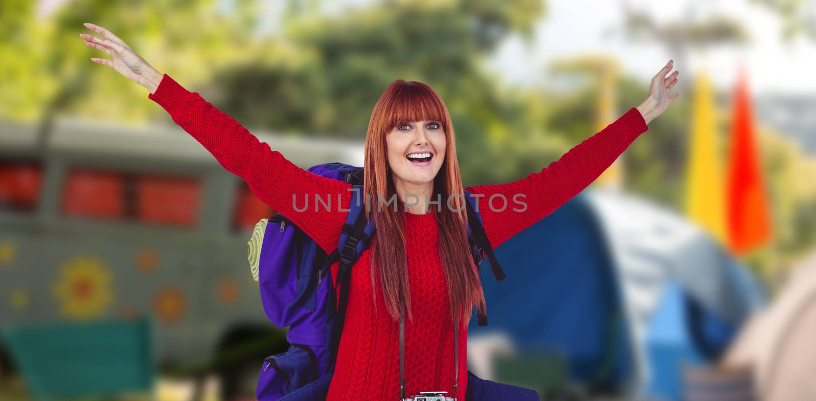Smiling hipster woman with a travel bag against empty campsite at music festival