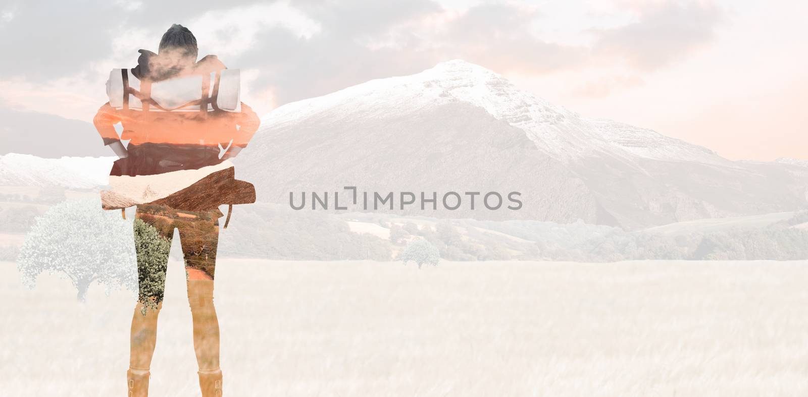 Rear view of a hipster woman with a travel bag against scenic backdrop
