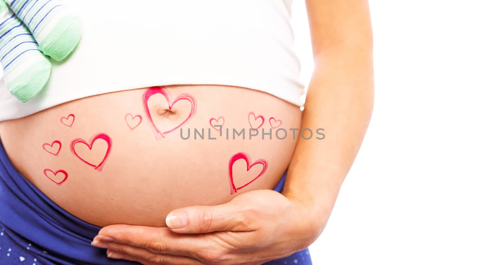 Pregnant woman holding baby shoes over bump against red hearts