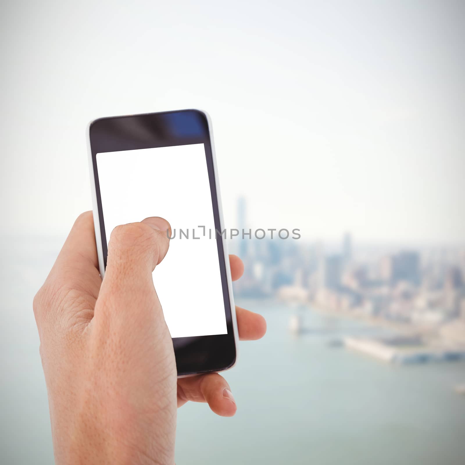 Cropped hand of man using mobile phone against city by the sea