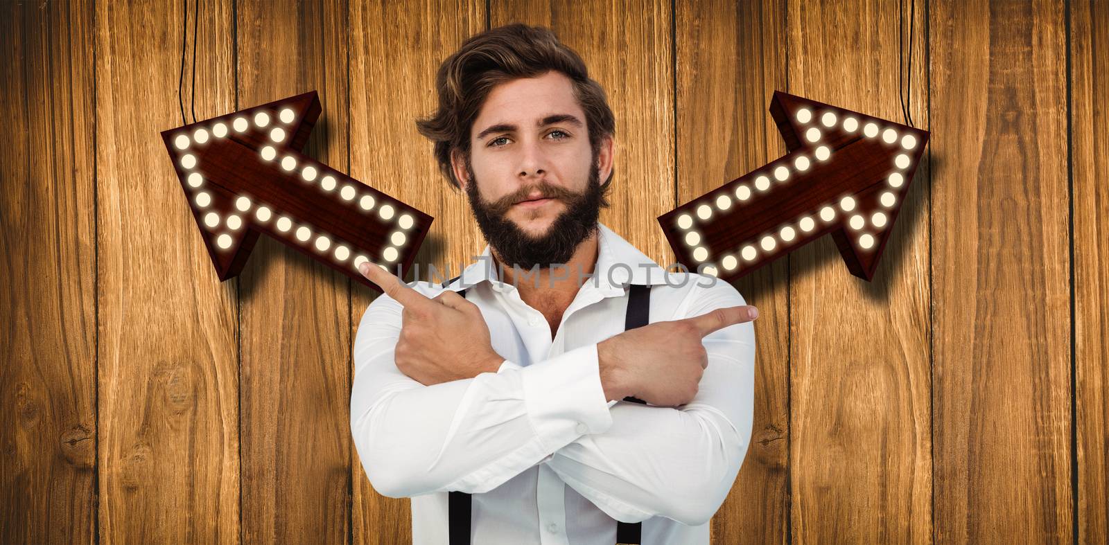 Confident hipster pointing sideways with arms crossed against wooden background