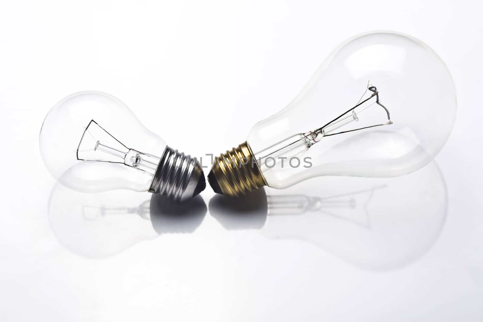 A small light bulb with silver screw and a large one with golden screw on white background