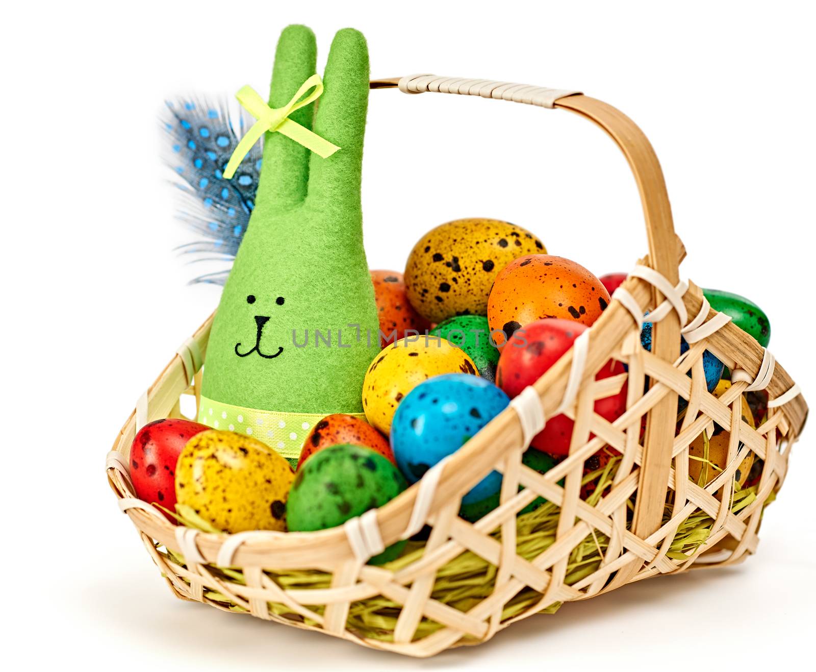 Easter rabbit and eggs in basket. Happy bunny handmade and hand painted multicolored quail eggs with straw and feathers, on white background. Unusual creative holiday greeting card 