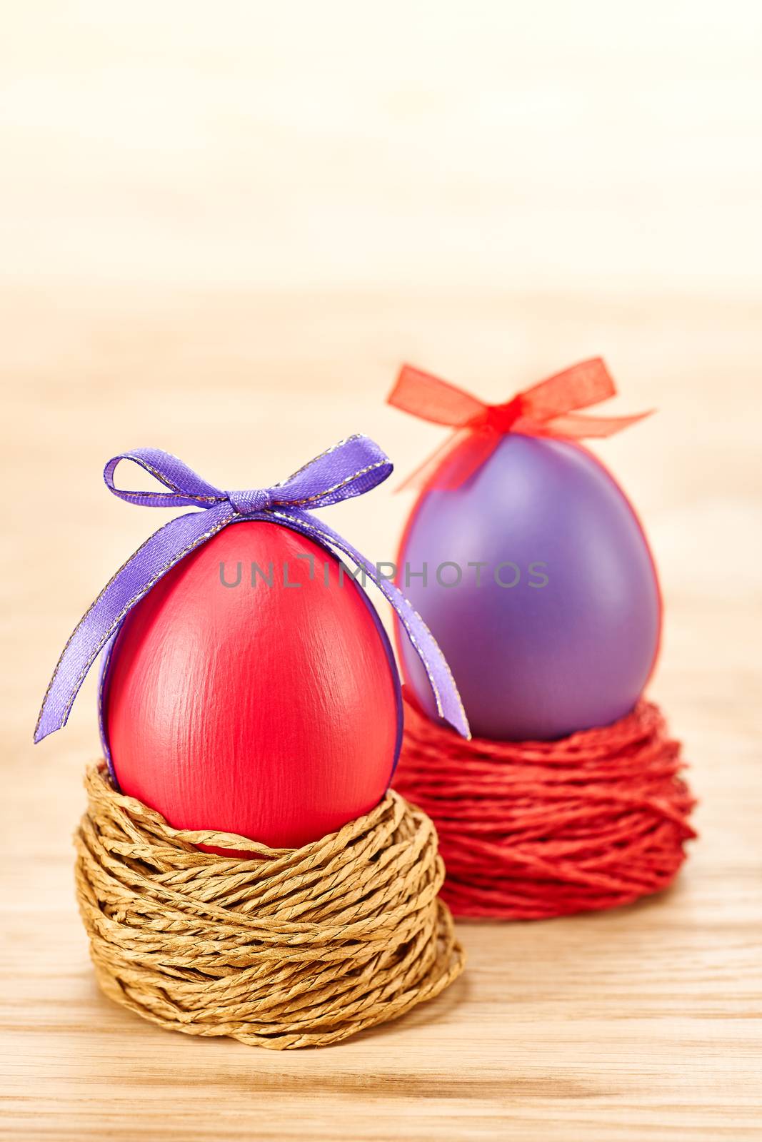Easter eggs in nests. Hand painted decorated multicolored eggs with bow on wooden background. Unusual creative holiday greeting card 