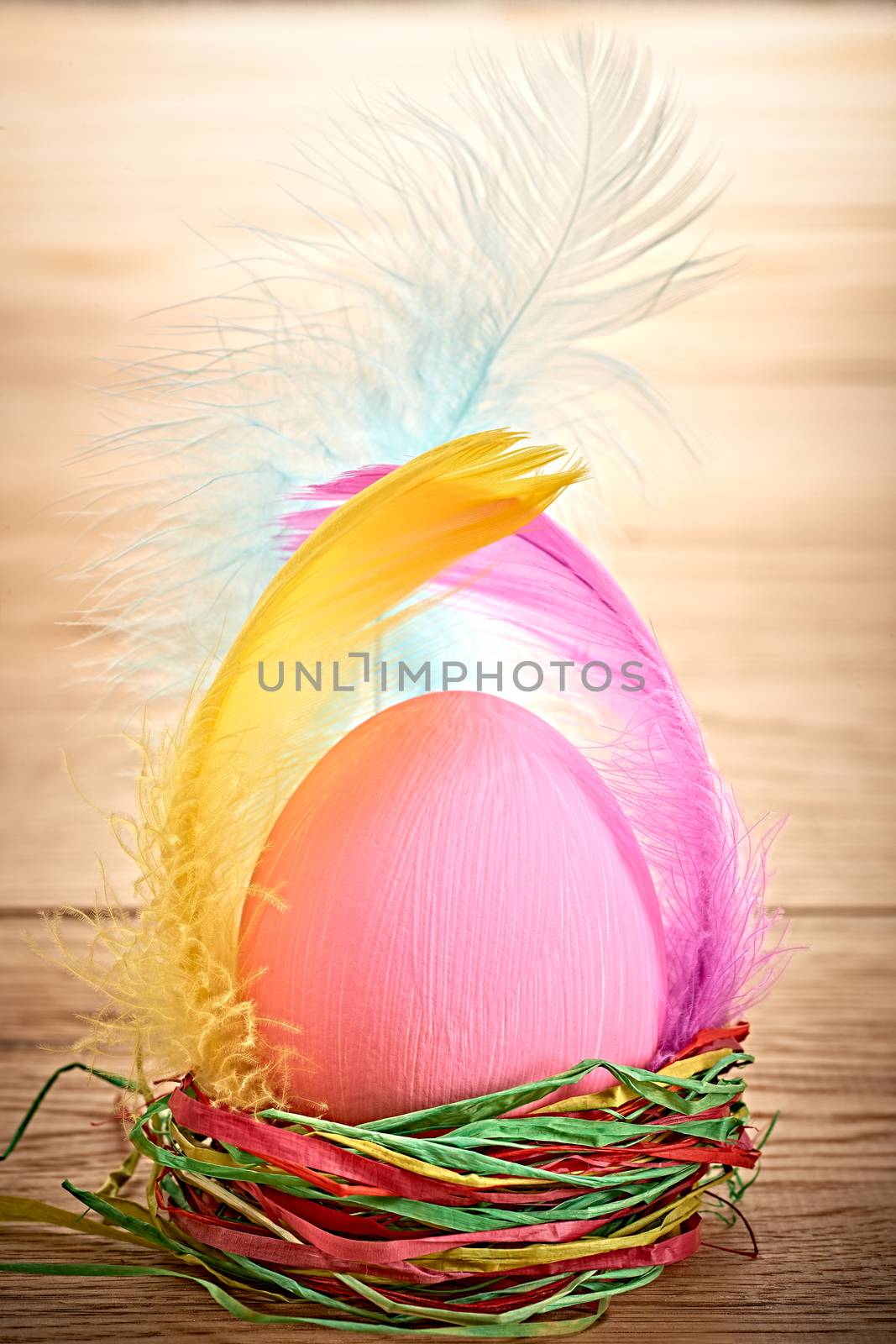 Easter egg in nest. HHand painted decorated egg with and feathers on wooden background. Unusual creative holiday greeting card 