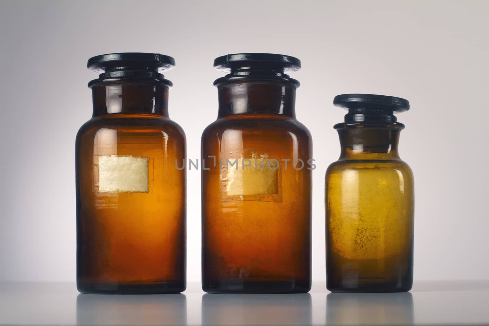 Three old medical brown glass jars isolated on grey  background