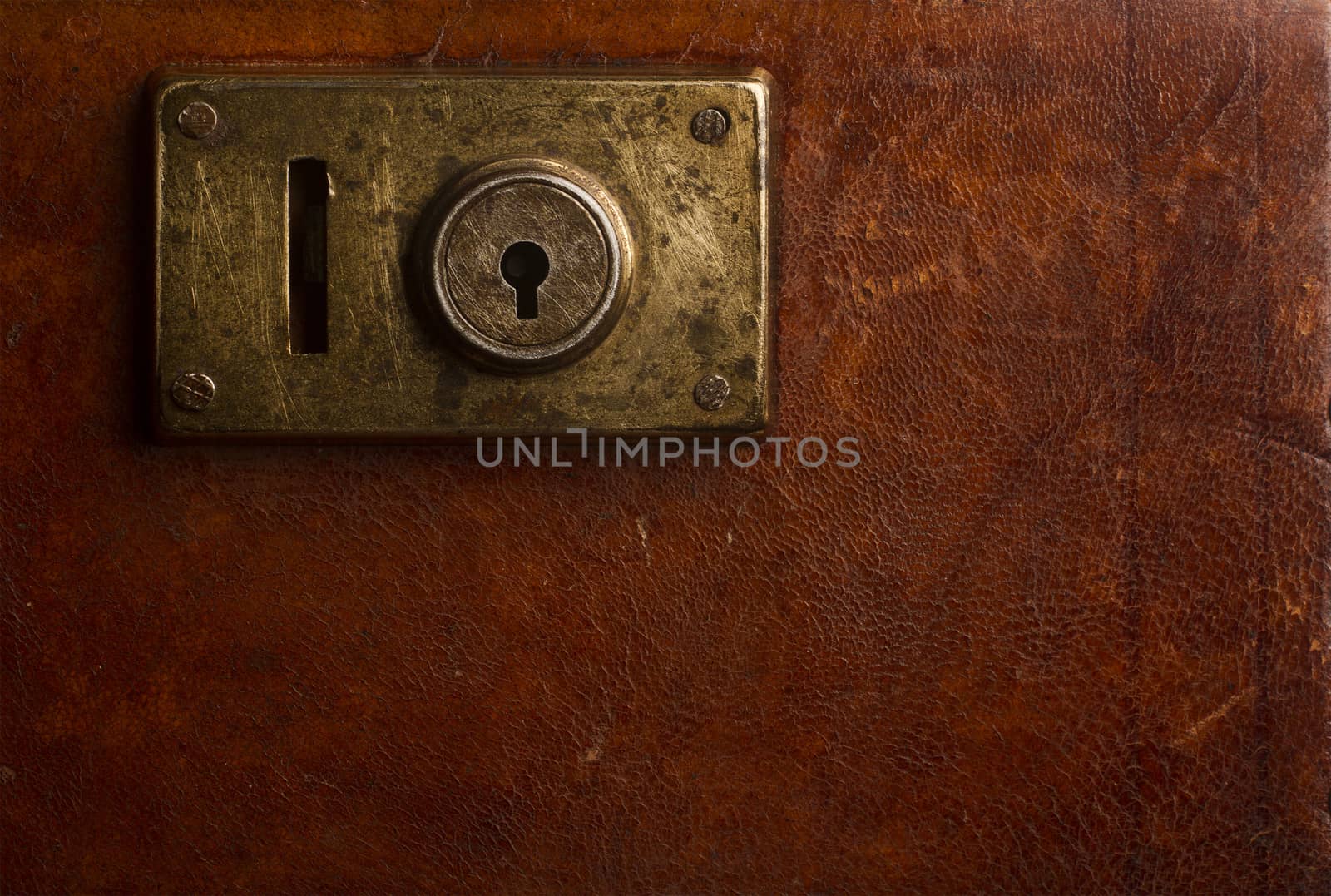Horizontal close up of an old locking mechanism on a vintage suitcase made of brown leather