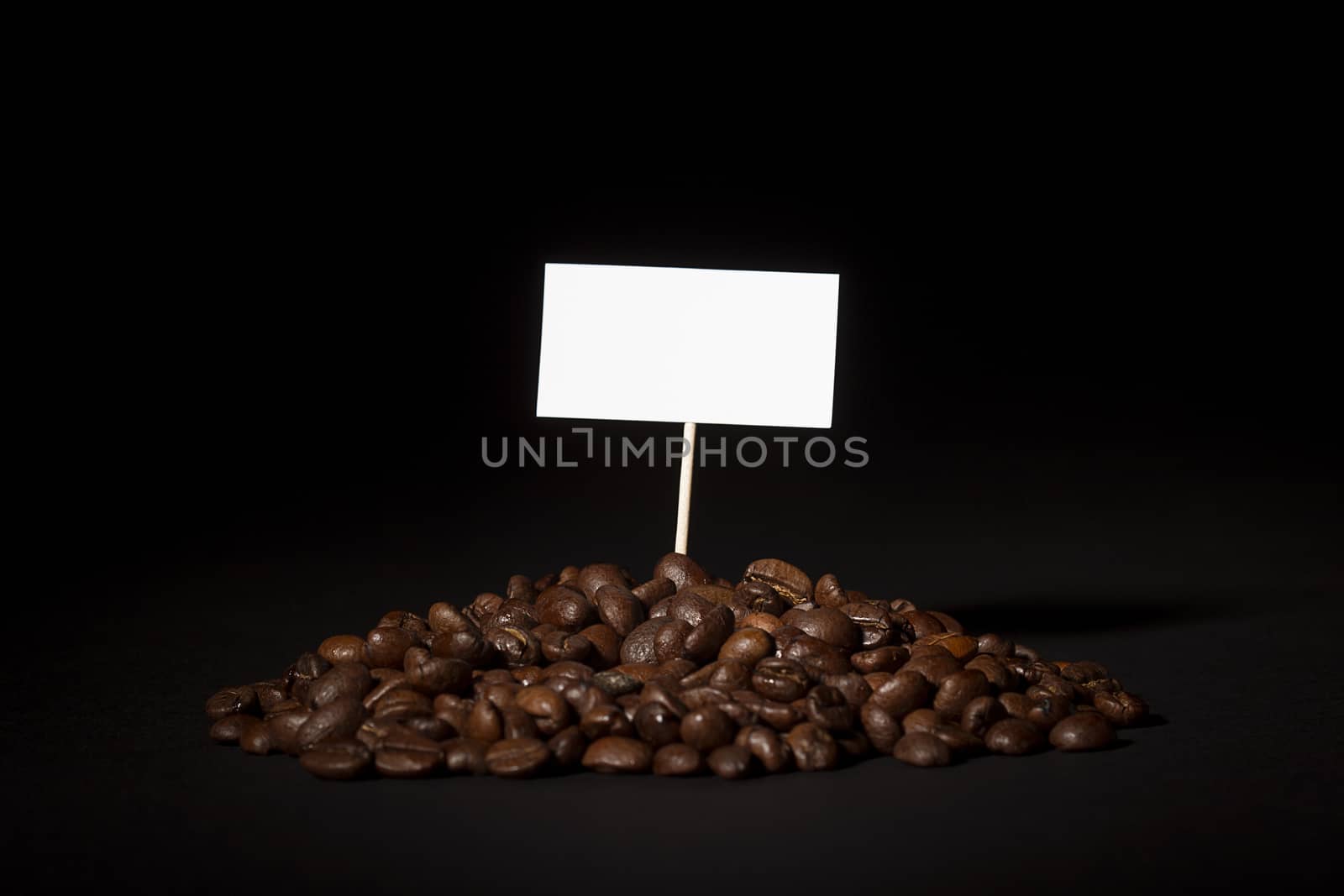 A pile of coffee beans with an empty sign on top of them shot on black background