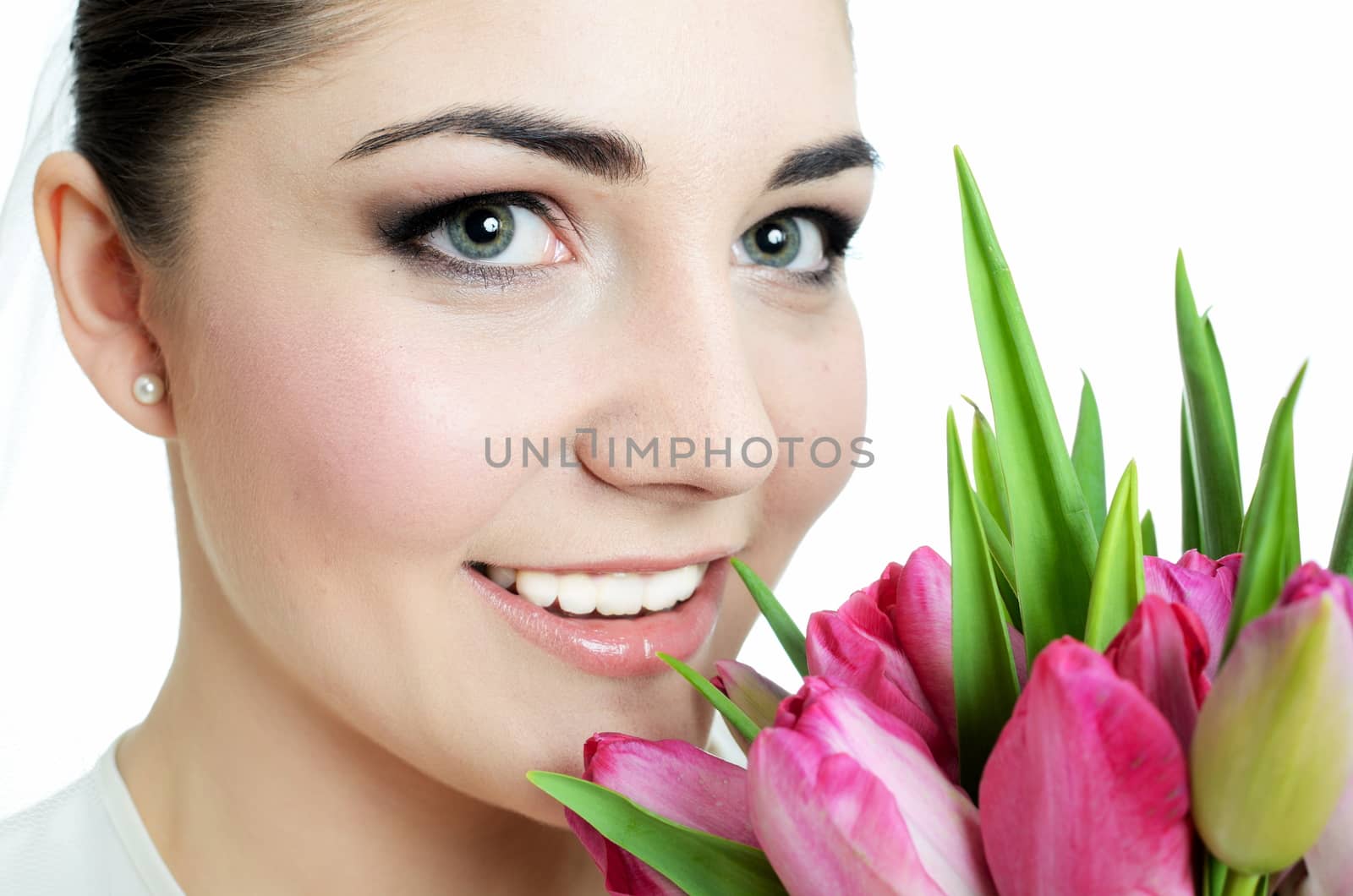 Beautiful, young bride closeup portrait. Young female holding flowers near her face.