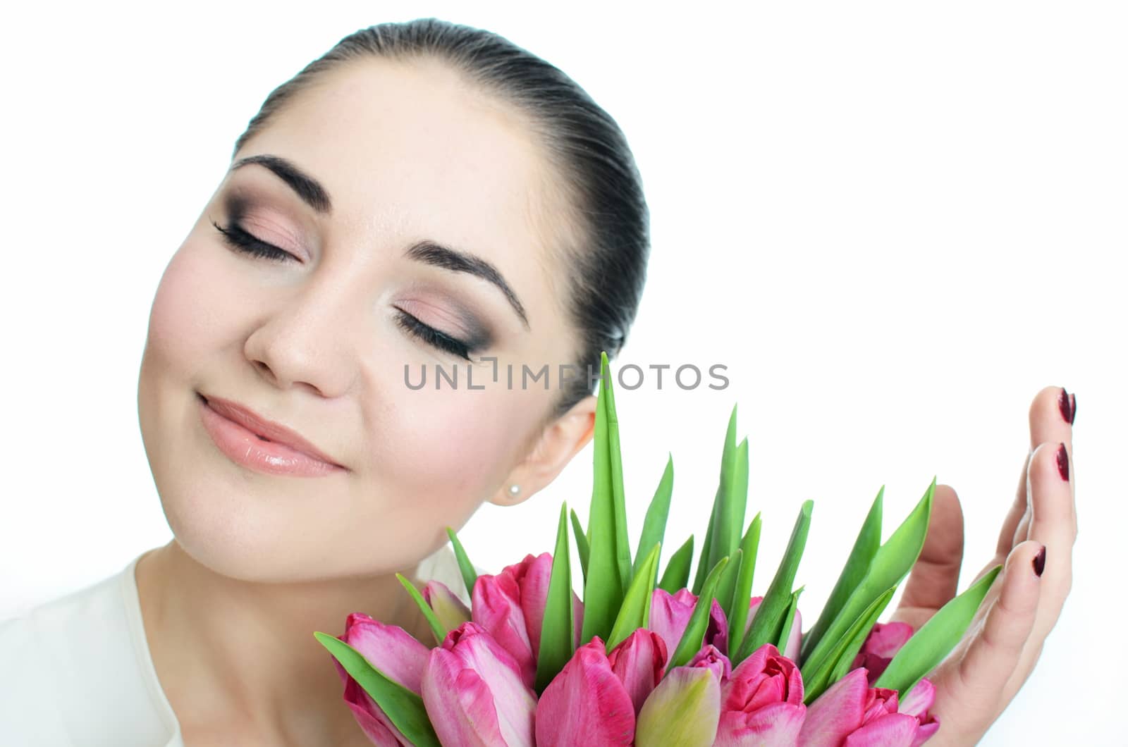 Beautiful female model in studio with whtie background. Young bride with sincere smile, holding tulips bouquet.