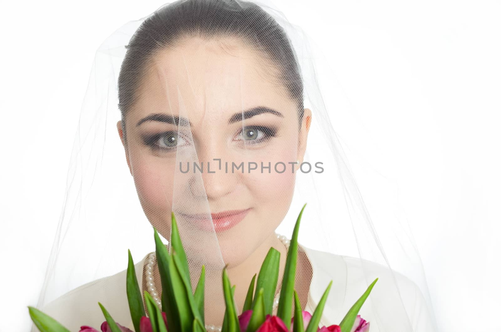 Female model, face covered with veil. Bride holds tulips bouquet. Portrait in studio with white background.
