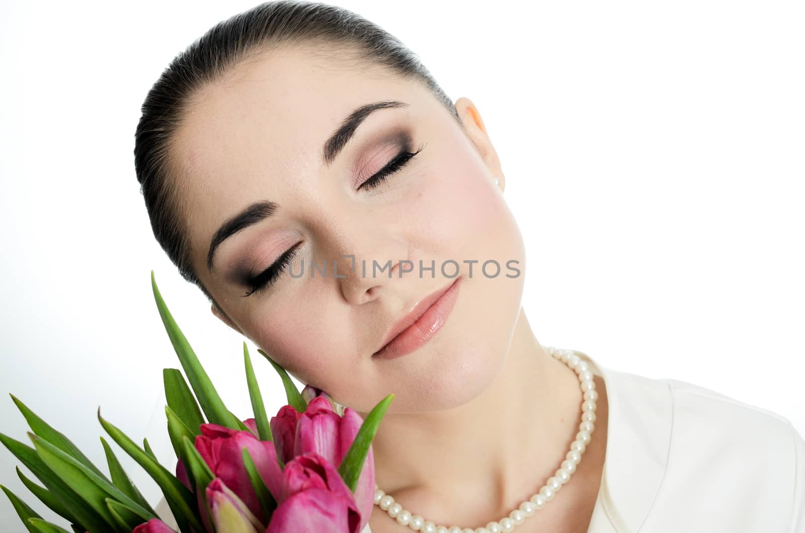 Beautiful female model in studio with whtie background. Young bride with sincere smile, holding tulips bouquet.