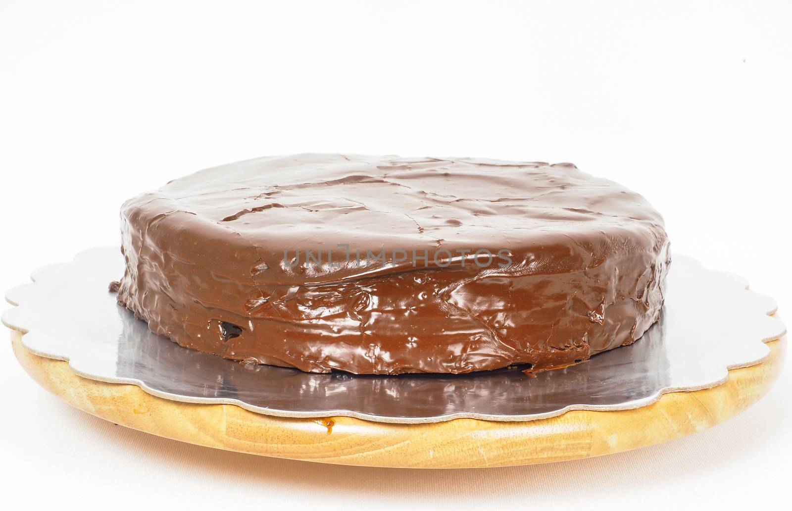 Sacher chocolate cake on a silver plate on wooden board towards white