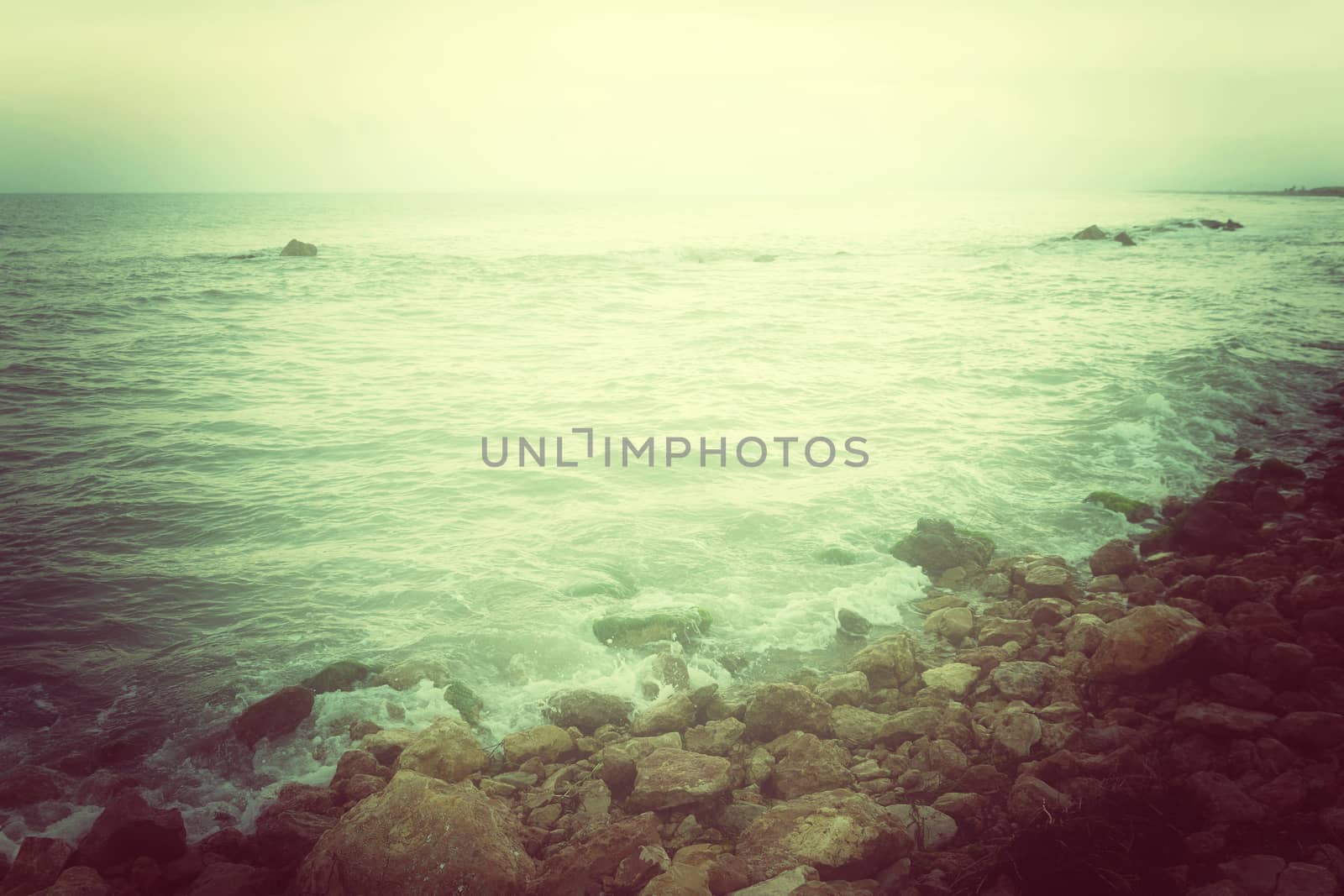 Rocky coast and stormy sea in green glow. Retro style photo.