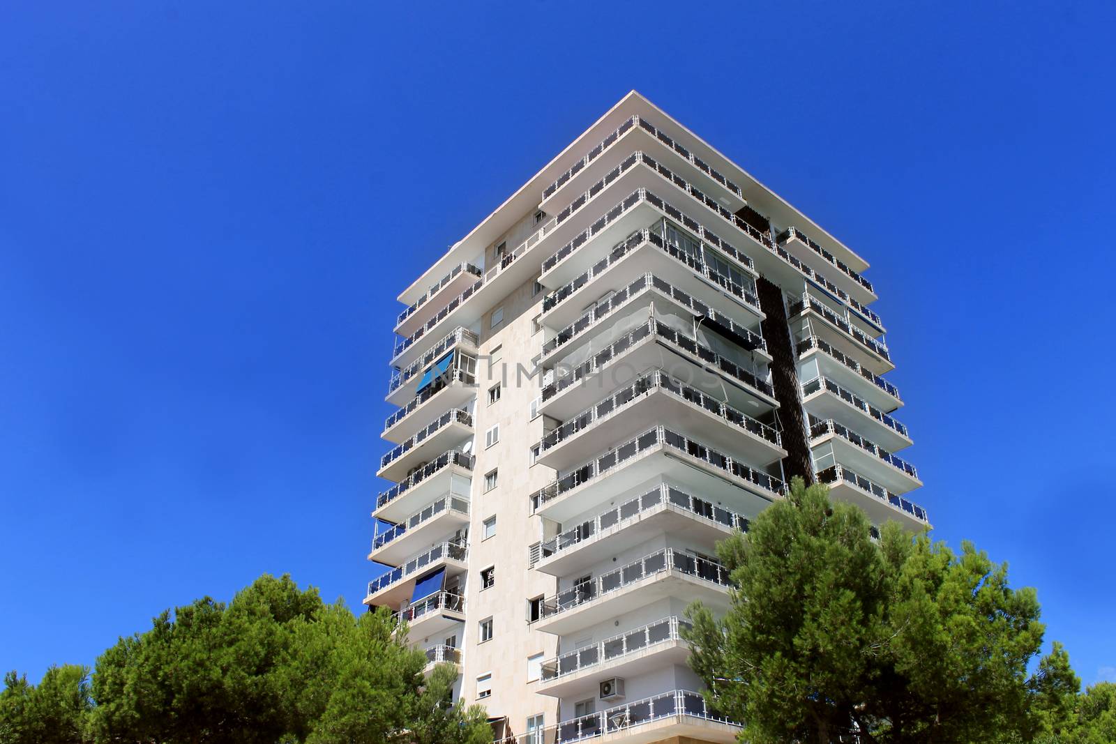 Exterior of a tall modern apartment building with blue sky background.