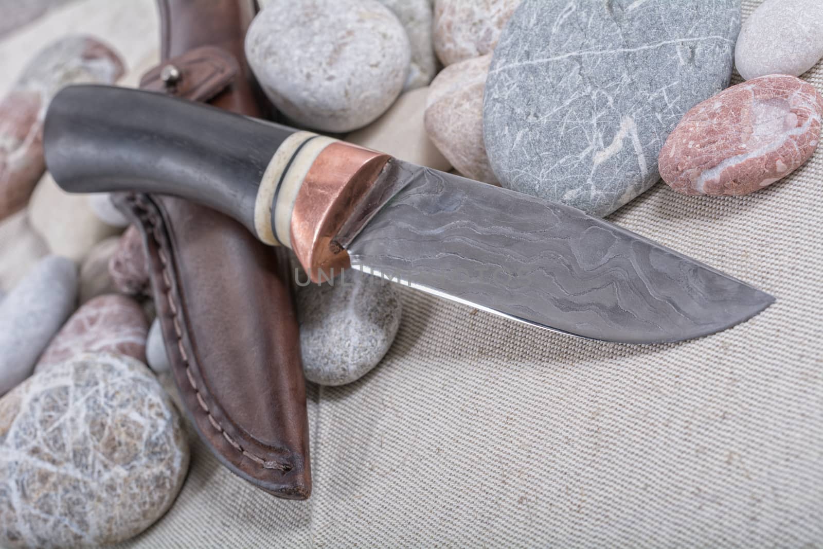 Work knife and a leather pouch on a stone and cloth background
