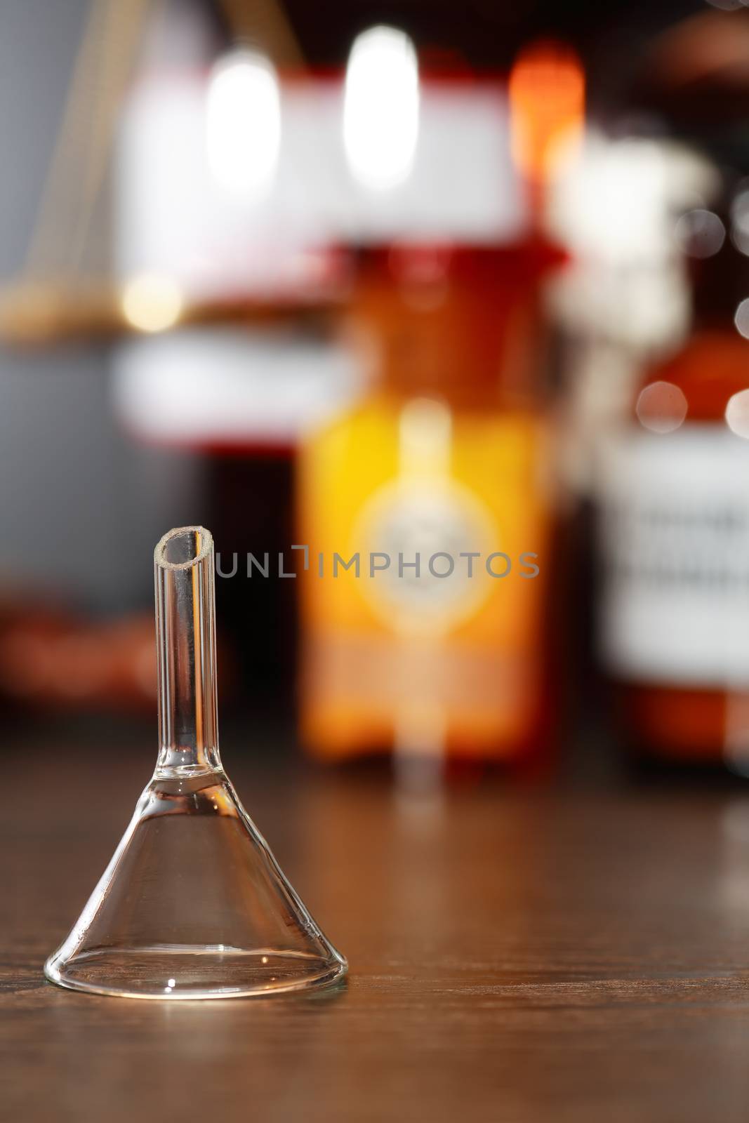 Chemical funnel against blurred background with flasks