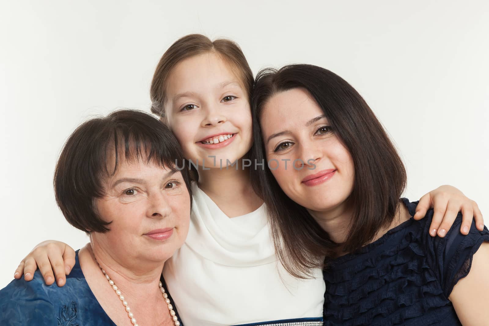 The granddaughter embraces the grandmother and mother on a white background