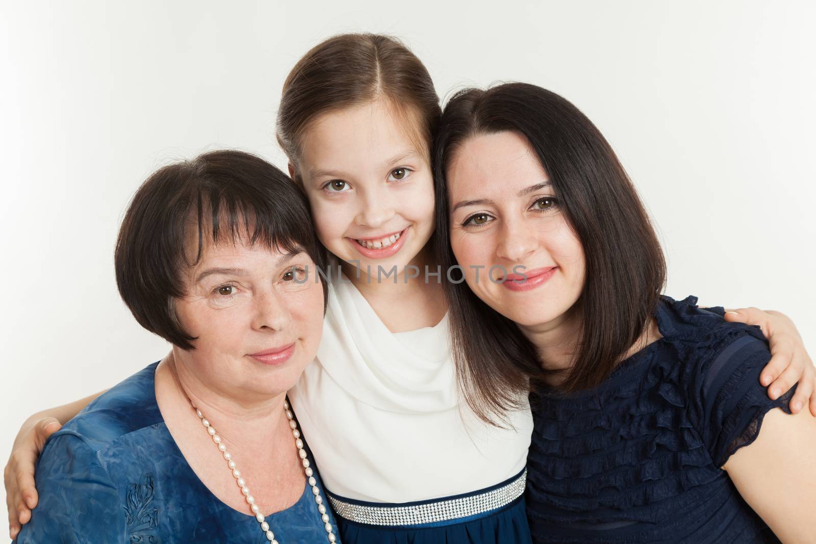 The granddaughter embraces the grandmother and mother on a white background