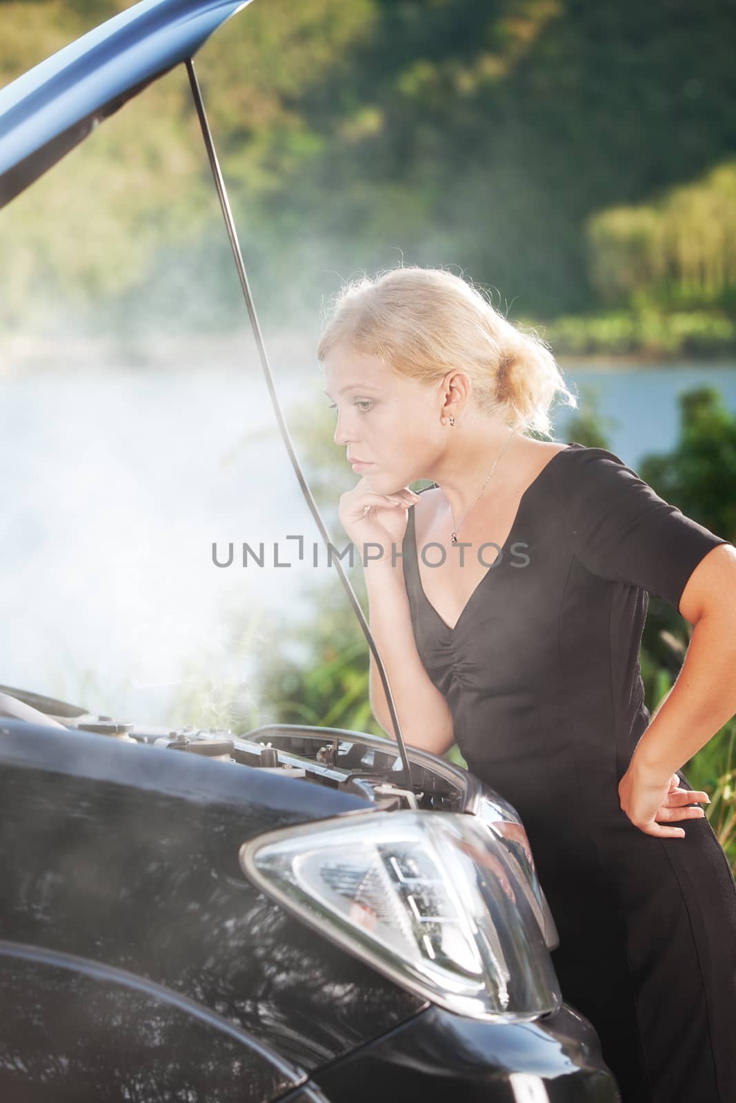 portrait of young beautiful woman with broken car aside