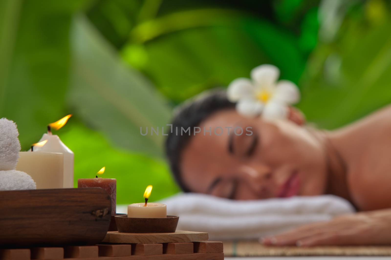 portrait of young beautiful woman in spa environment. blurred face, focused on candles.