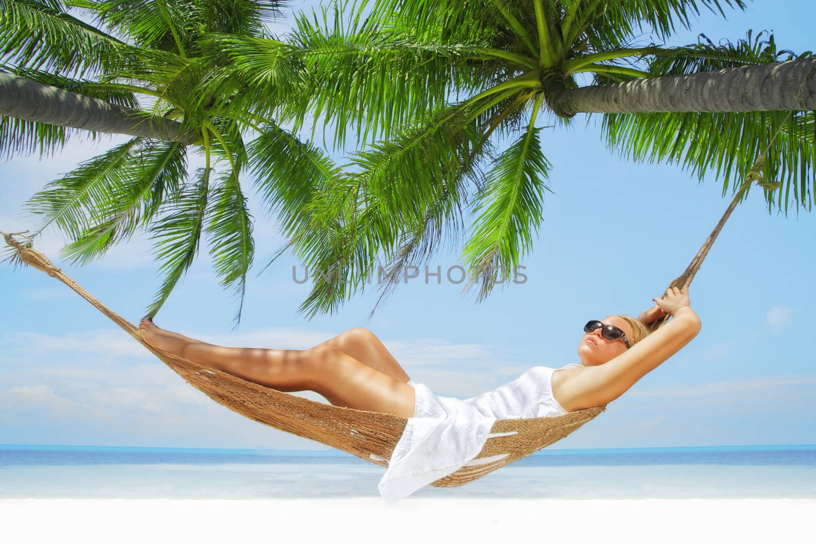 view of nice young lady swinging  in hummock on tropical beach