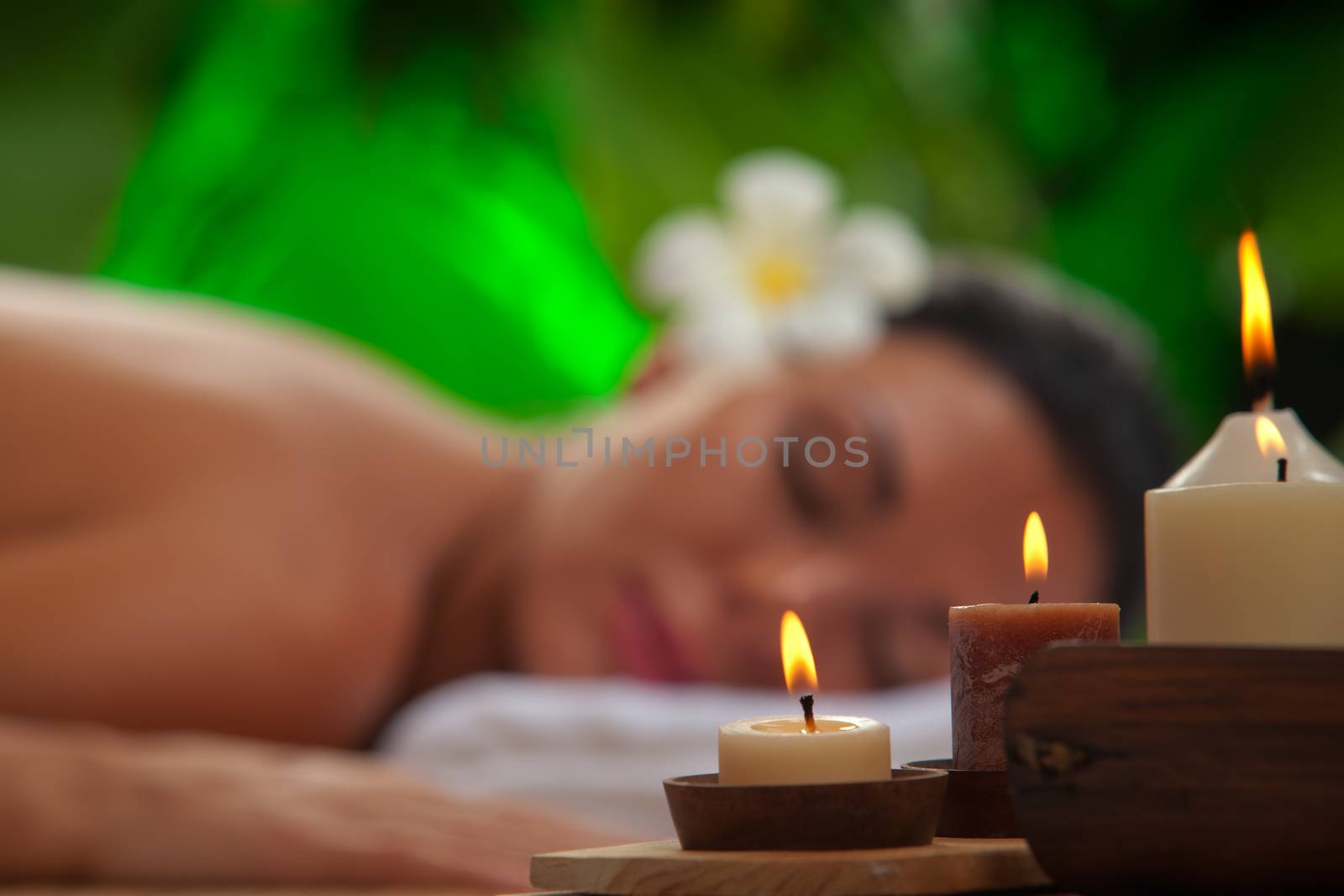 portrait of young beautiful woman in spa environment. blurred face, focused on candles.