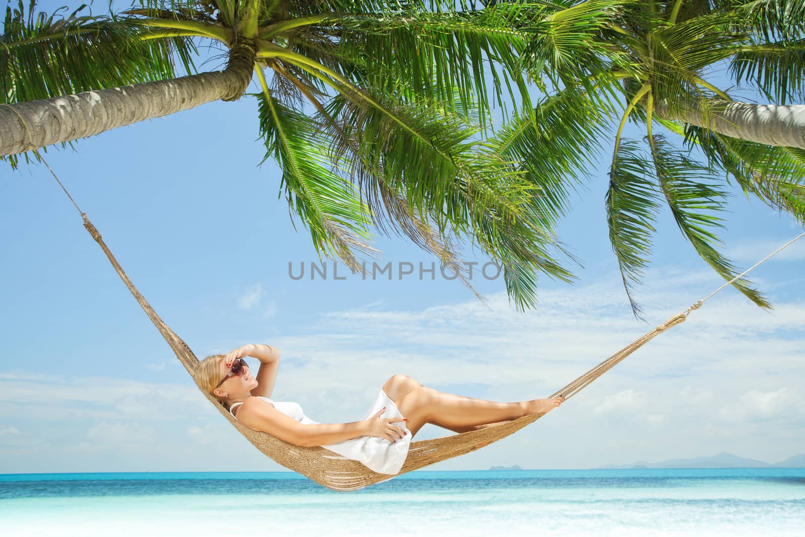 view of nice young lady swinging  in hummock on tropical beach