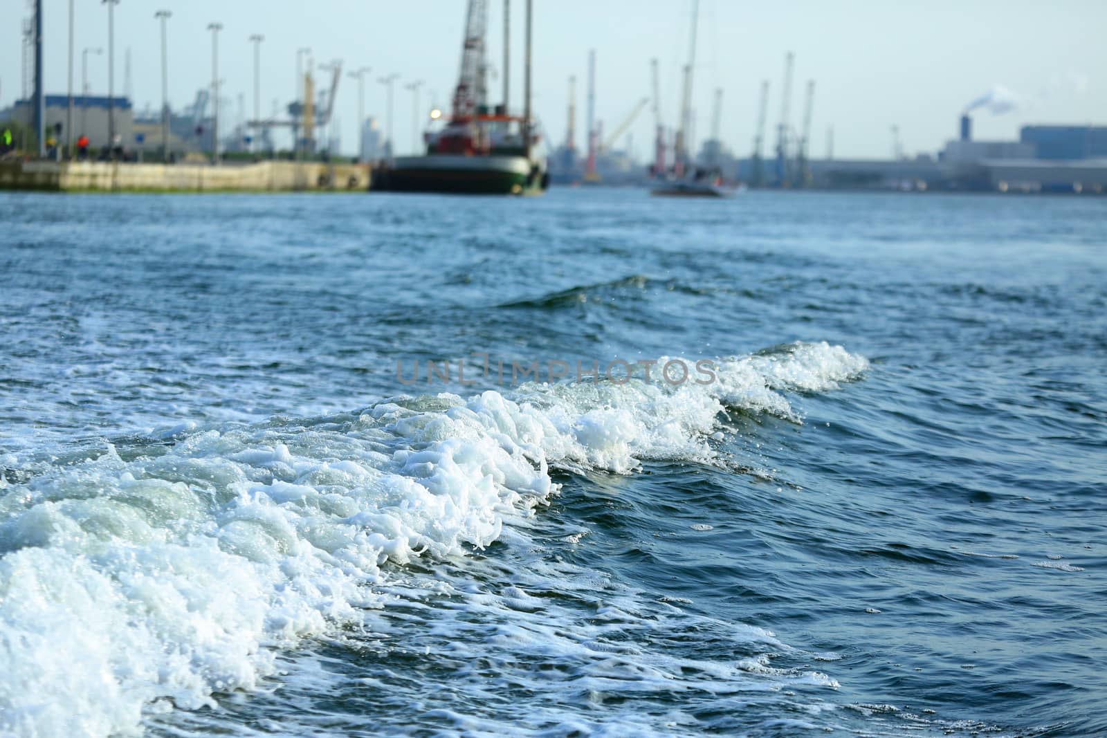 Blue sea with waves and foam against the port by sergasx