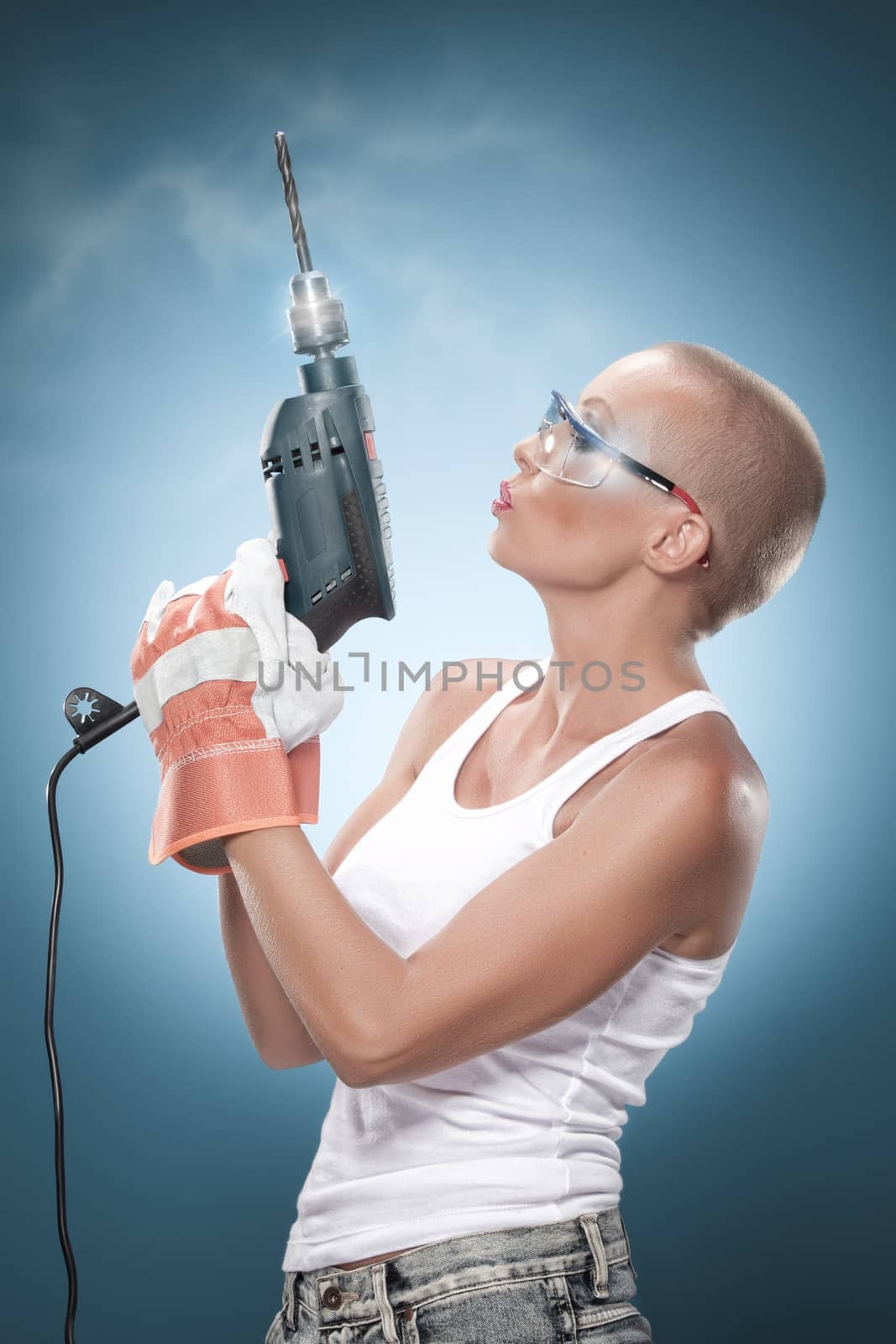 portrait of young beautiful  woman with drill on blue back